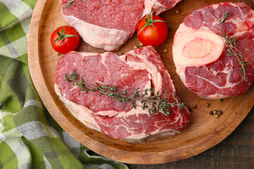 Pieces of raw beef, spices and tomatoes on wooden table, top view