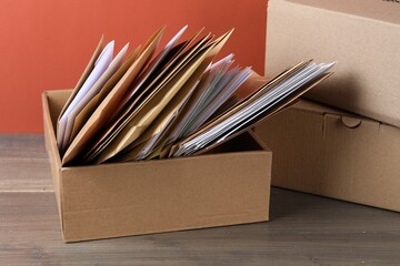 Different paper envelopes in box and parcels on wooden table. Post office