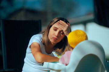 Tired Mom Feeding Baby in the Garden and Getting Stressed Out. Unhappy exasperated mother worried...