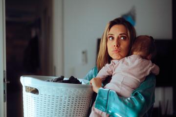 Mom Holds Baby and Laundry Basket Feeling Overwhelmed by Housework. Unhappy mother feeling tired...