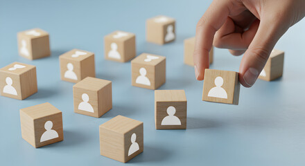 Hand Placing Wooden Cube with People Icon on Blue Surface for Business Concept