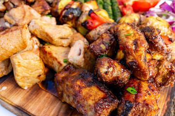 Grilled meats served on a wooden platter with colorful vegetables