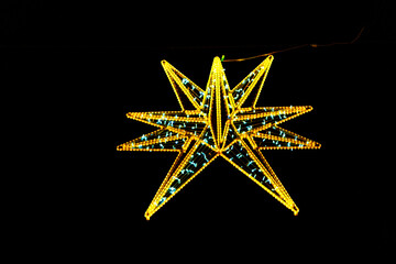 Illuminating the night, a magnificent starburst of golden and teal LED lights. Geometric star, crafted from glowing LED lights, creating a striking silhouette against the dark backdrop