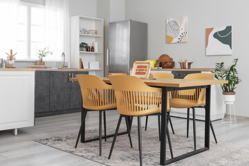 Dining table in interior of kitchen with fridge and counter