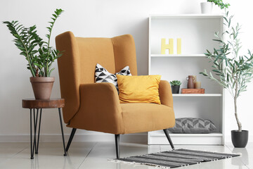 Interior of stylish living room with comfortable armchair, houseplant on coffee table and olive tree