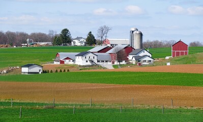 Traditional red barns and modern structures stand amidst meticulously cultivated fields near Lancaster County, Pennsylvania, U.S