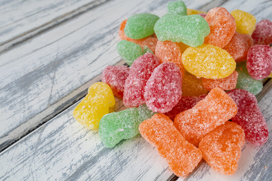 Assorted sour sugar candies close up on wooden board.