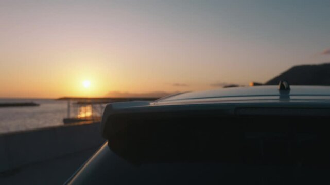海岸に止まる車のシルエットと夕日