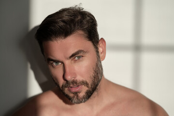 Closeup portrait of attractive man for cream on male face cosmetics advertising. Beautiful man close up portrait on white background. Naked shoulders, skin care, health, cosmetics for skin.