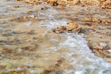 closeup sea sand beach with rocks stones on coast or island with nature little waves for summer holiday travel and daylight seascape landscape background at Sai Kaew Beach Thailand CPL and wave motion