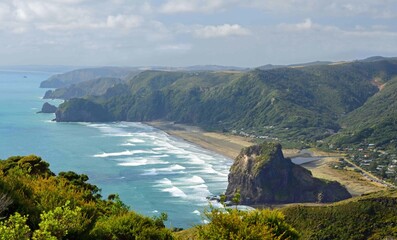 looking down on iconic lion rock, coastal headlands,  and black sand of  piha beach from on a summer day  from the mercer bay loop trail on the west coast of north island of new zealand, near auckland