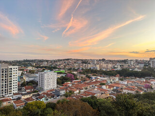 Beautiful sunset casting warm golden and pink tones over an urban skyline with soft clouds and a tranquil evening sky
