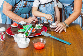 Family decorating cupcakes with frosting and sprinkles in the kitchen