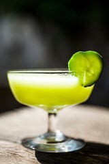 Refreshing cucumber smoothie garnished with cucumber slice on wooden table