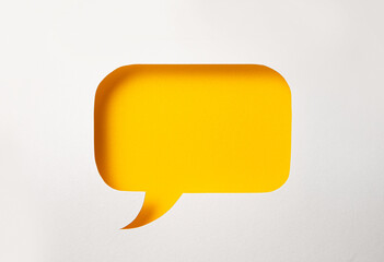 Paper speech bubble in the shape of a rectangle on a yellow background. Flat white chat icon in the form of an empty speech bubble.