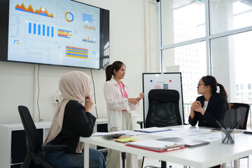 Team of professionals in modern office discussing data analytics displayed on large screen, fostering collaboration.