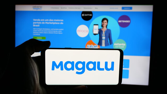 Stuttgart, Germany - 03-24-2025: Person holding cellphone with logo of retail company Magazine Luiza S.A. (Magalu) on screen in front of webpage. Focus on phone display.