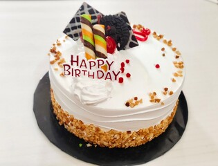 Birthday Cake with White Cream, Chocolate Toppings, and Happy Birthday Decoration