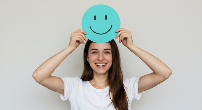 Happy Young Woman Holding a Smiling Face Card Above Her Head, Positive Emotions and Mental Health Concept