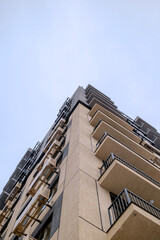 Modern residential high-rise building with balconies and air conditioning units, low angle view against clear sky