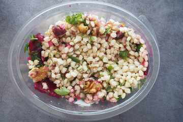 Delicious quinoa salad with walnuts and pomegranate on a marble table