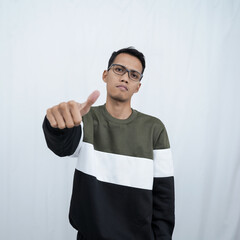 An Asian young man with glasses wearing a sweater smiling expression while giving a thumbs up sign. Isolated on white background.