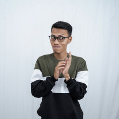 An Asian young man with glasses wearing a sweater with an expression of hiding something, mysterious or thinking evil. Isolated on white background.