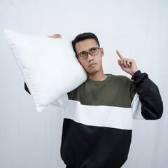 A young Asian man with glasses wearing a sweater holding and enjoying a pillow to fall asleep. Isolated on white background.