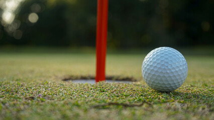 Golf ball on green grass in the evening golf course with sunshine background.