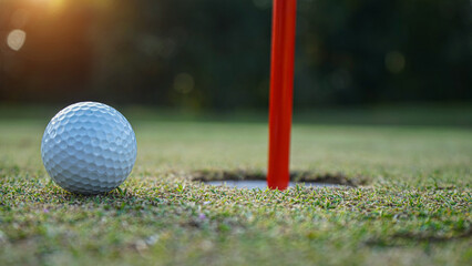 Golf ball on green grass in the evening golf course with sunshine background.