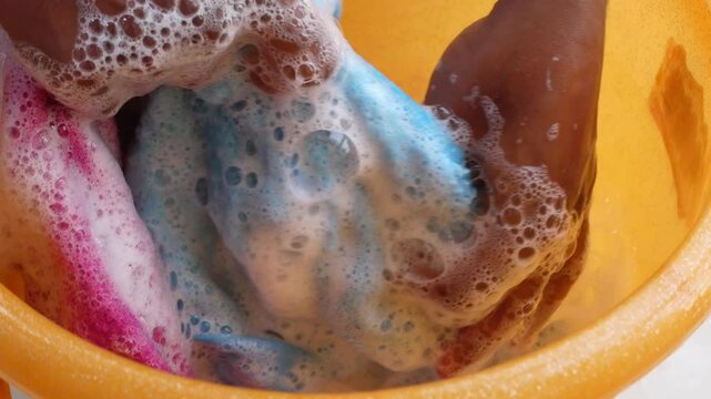 Cleaning colorful cloths in a soapy bucket