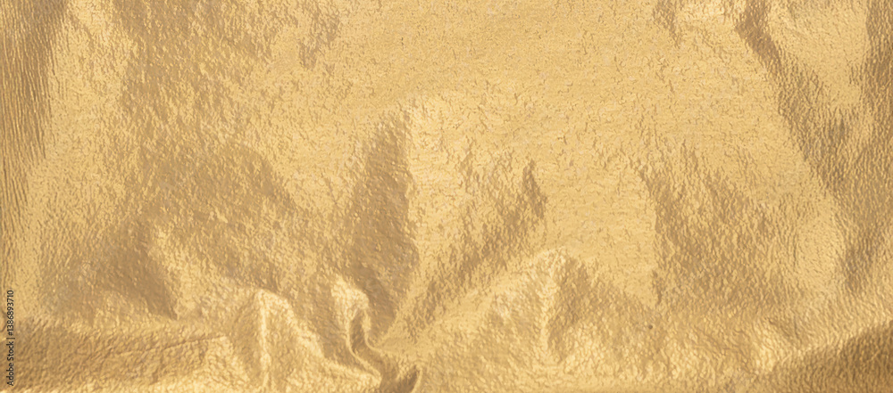 Poster Gold foil background with wrinkled texture and soft matte finish. Reflective metallic sheet with gradient light and sparkle creates a chic panoramic banner for holiday card..