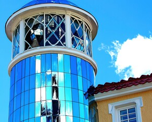 Obraz premium Stunning Modern Building With Reflective Glass Tower Against a Bright Blue Sky Showcasing Architectural Brilliance and Unique Design Elements