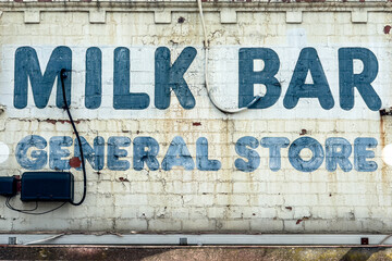 A vintage Australian corner shop sign with the words 'Milk Bar' and 'General Store'