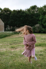Obraz premium girl running on the field from the house. looking away. hair blowing.