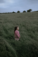 Girl standing in the field with tall grass. she looks forward.