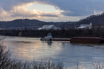 A river barge slowly floats down stream under clouds