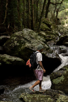 Man hiking over rocks along a waterfall trail in Australia