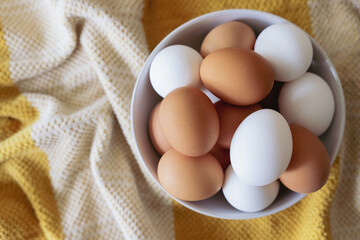Brown and white eggs in a white bowl overhead photo