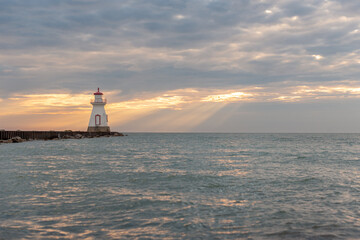 Fototapeta premium Beautiful lighthouse sits at end of pier with moody sunset sky