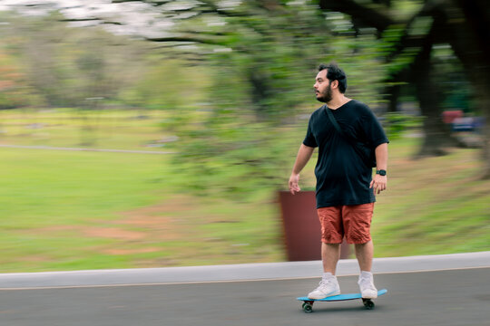 Panning Shot Of Man On A Skateboard Going Downhill