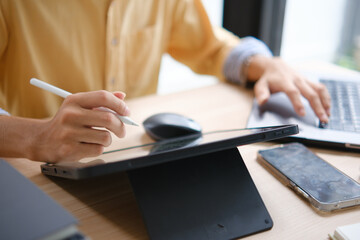 Male web designer drawing with graphic tablet at table in office.