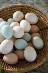 Variety of colorful eggs in a woven basket on counter.