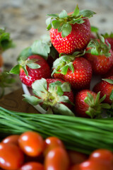 Fresh strawberries, chives, and cherry tomatoes on kitchen counter