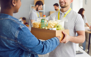 Close up shot of a happy Caucasian man volunteer handing a food box to an African American refugee...