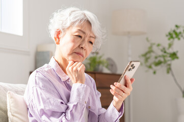 スマホを操作して困っているシニア女性