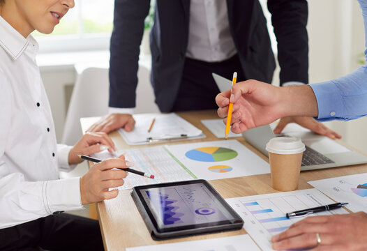 Company members workers team gathered at conference room desk doing statistical analysis of data reviewing financial pie charts on tablet computer, sales graphs solving at group meeting together