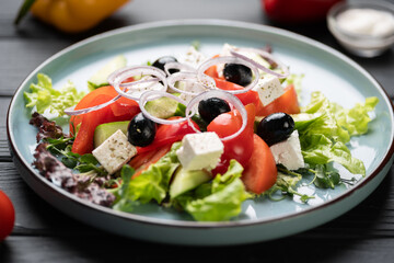 Fresh Vegetable Greek Salad. cherry tomatoes, red onion, feta cheese and cucumber on blue plate on wooden table