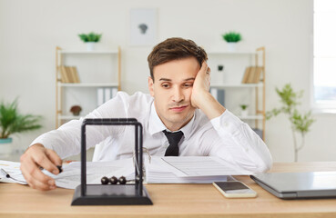 Tired or bored man working with documents in an office, showing signs of boredom and burnout. He...