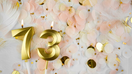 73rd birthday card. Golden candles number 73, figure seventy-three on pastel confetti background. Celebrating anniversary and birthday concept.